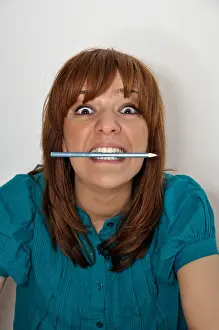 Brunette Prints: Young woman biting pencil