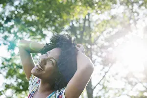 Simple Living Prints: A young woman in a flowered summer dress with her hands behind her head smiling and looking up