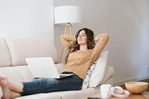 25 30 Years Prints: Young woman with laptop relaxing on sofa at home