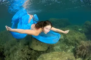 Veil Prints: A young woman with long hair in a blue dress dives underwater in Black Sea