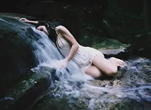 Beautiful Woman Prints: Young woman lying on rocks in a waterfall