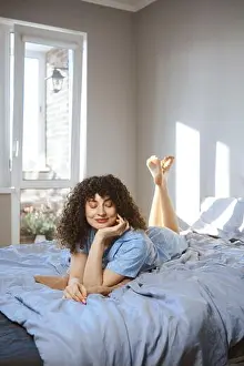 Belly Prints: A young woman is lying on her stomach on a bed covered with blue sheet