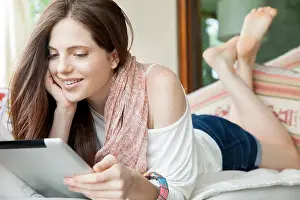 Contentment Prints: Young woman lying on stomach, looking at digital tablet
