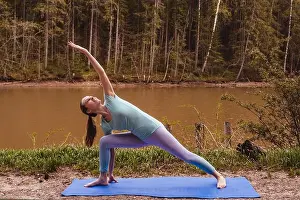 Retiree Prints: Young woman making yoga near river alone. Sport in lockdown