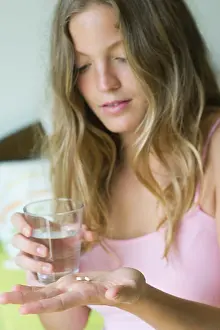 One Young Woman Only Prints: Young woman preparing to take pills with glass of water