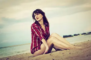 Chequered Prints: Young woman in a red checked shirt relaxing on the beach at sunset