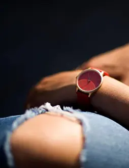Knee Prints: young woman resting dressed in a torn blue jean and a salmon colored watch on a dark colored background