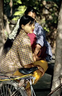 Young Girl Prints: Young woman sitting on bike with tanaka painted on her cheeks in Burma, Myanmar