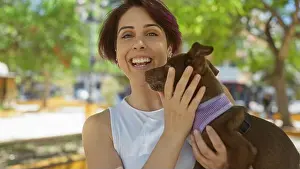 Emotional Prints: A young woman smiles joyfully while holding her dog at an outdoor urban park