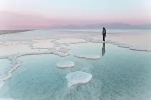 20 25 Years Prints: Young woman standing on salt formations in dead sea at sunset