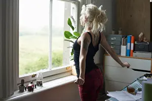 Three Quarter Prints: Young woman stretching at window in home office