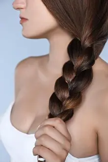 Braid Prints: Young woman with strong healthy braided hair on light blue background, closeup
