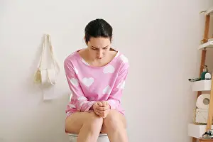 Pajamas Prints: Young woman suffering from constipation on toilet bowl at home