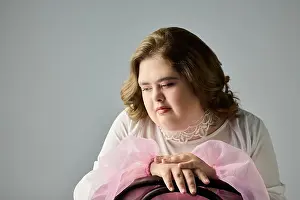 Down Syndrome Prints: A young woman with Down syndrome wears pink, showing a thoughtful and happy expression