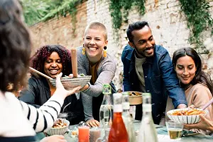 Weekend Activities Prints: Young woman with toothy smile passing bowl to friend at dinner party