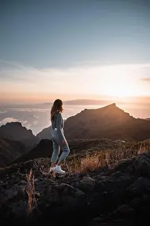 Sunset View Prints: Young woman with urban outfit looking at a beautiful sunset from the top of Teno on the canary island of Tenerife