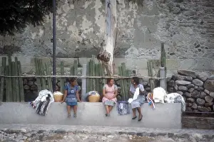 Zapotec indigenous women sitting on a wall chatting in the the village of Mitla, Oaxaca, Mexico